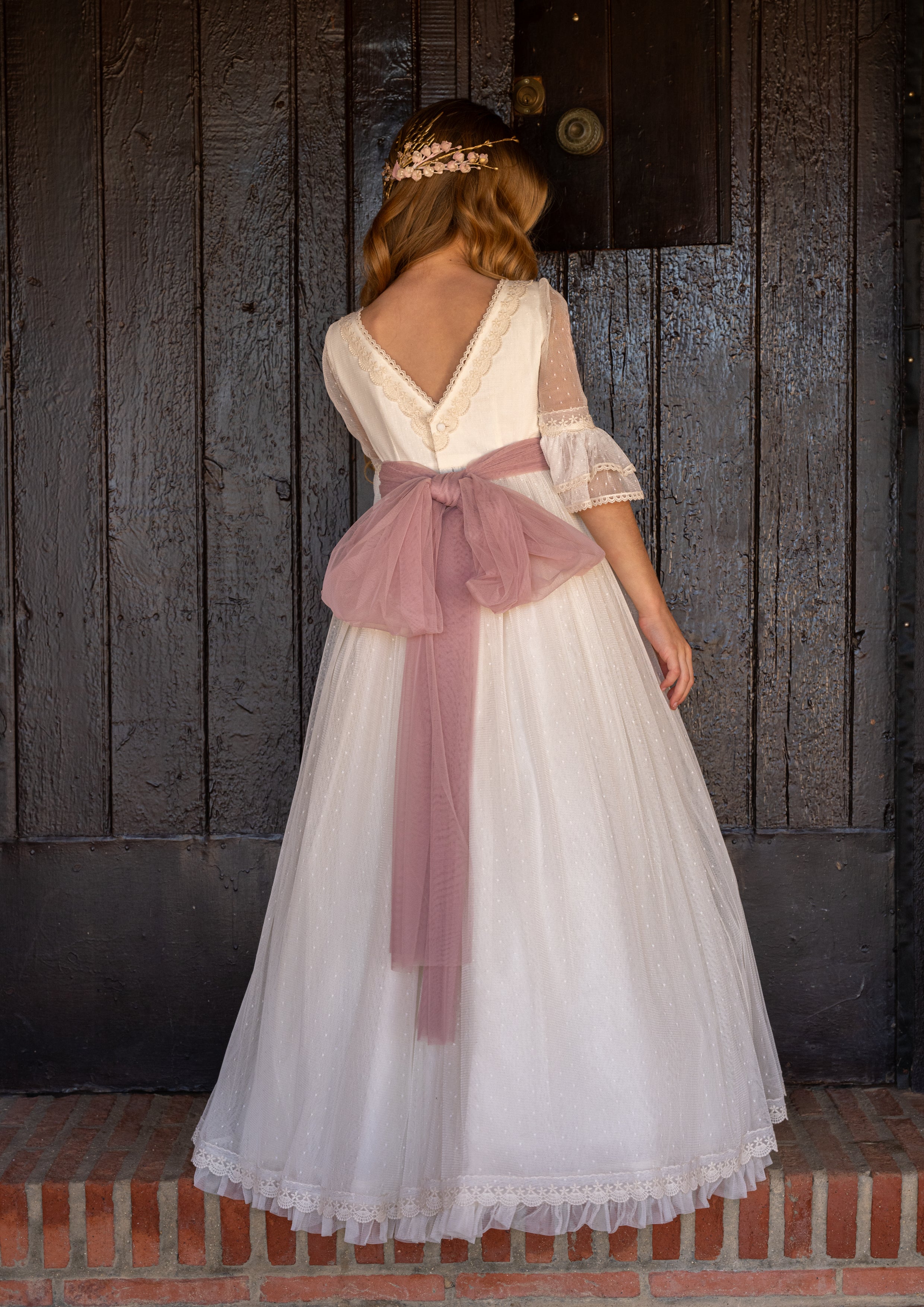 Vestido largo blanco con lazada rosa y plumeti para comunión NORA - marca Manuela Macías (corona de flores incluida)